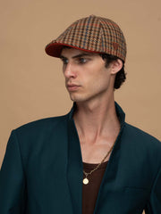 Man wearing Royalty Brick Casket Hat and dark green blazer against a beige background