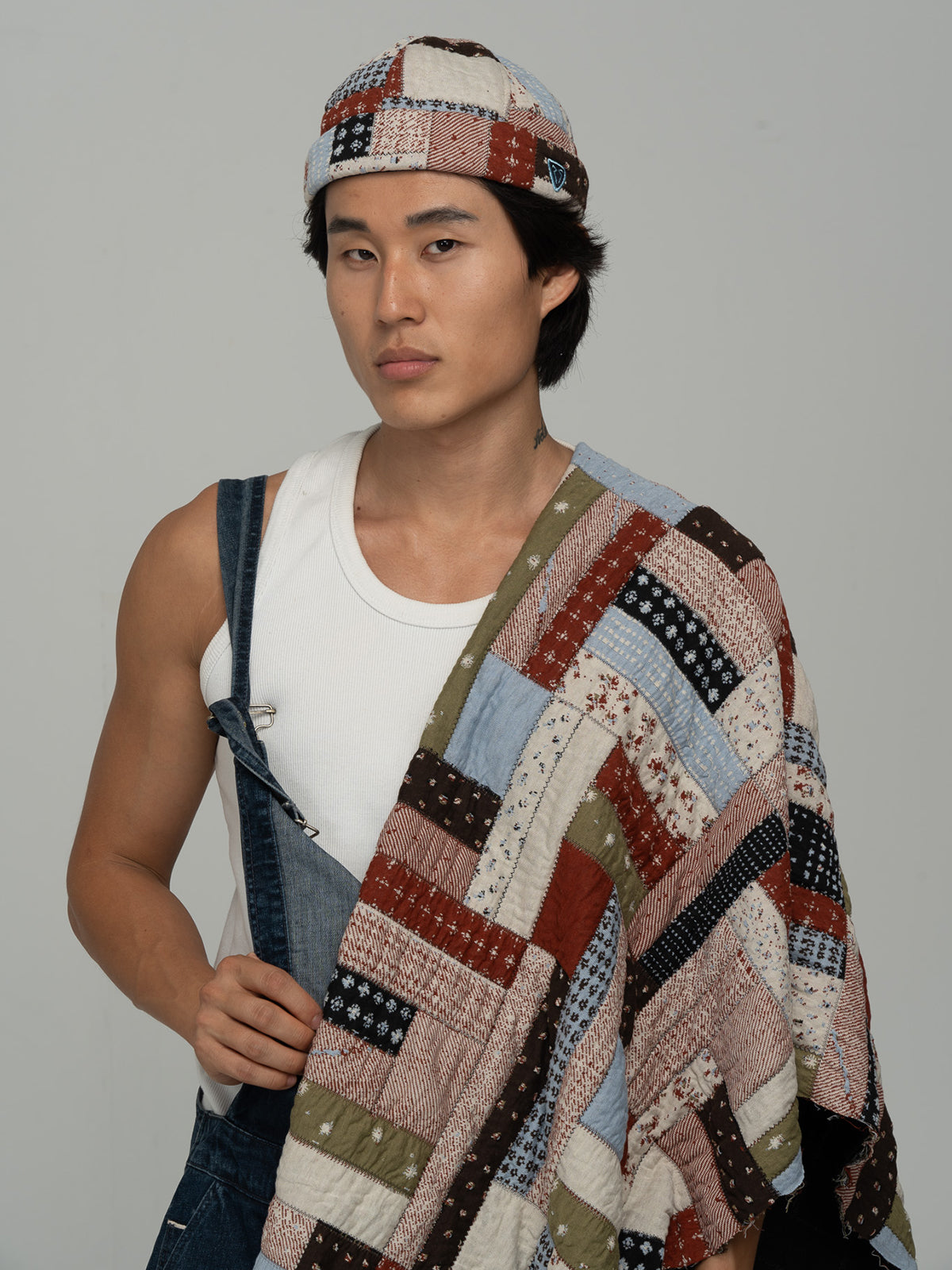 Person wearing Rustwork Multicolor Docker Hat over a white tank top with a plain background