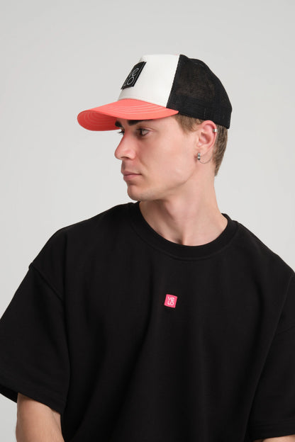 Person wearing a black, white, and red cap with a plain black t-shirt on a light gray background