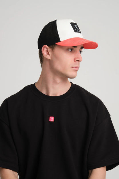 Person wearing a black cap with red brim and black t-shirt with red logo on a gray background