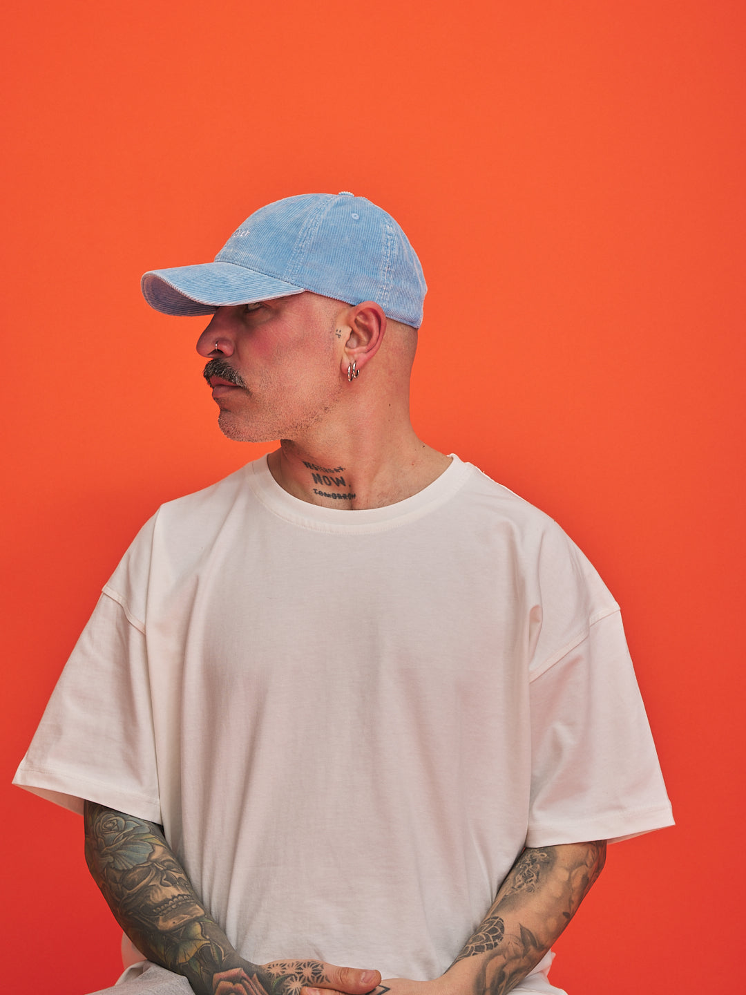 Man wearing a light blue cap and white t-shirt against an orange background