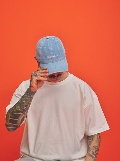 Person wearing a blue cap and white t-shirt against an orange background