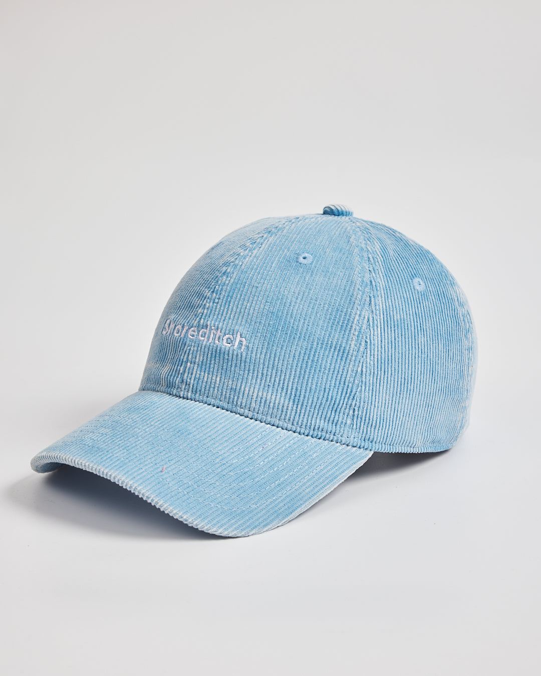 Light blue denim cap with branding on a light gray background