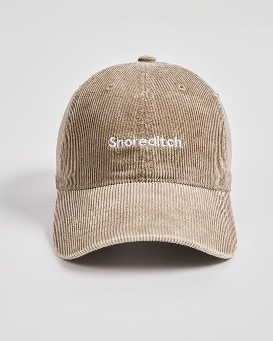 Beige corduroy cap with 'Shoreditch' text on a light gray background