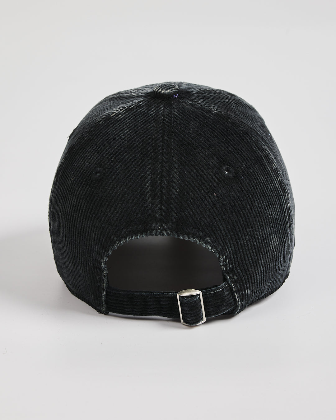 Black corduroy cap on a light gray background