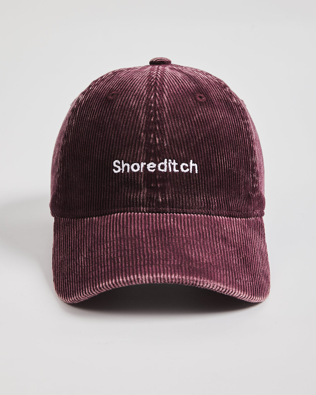 Maroon corduroy cap with 'Shoreditch' text on a light gray background