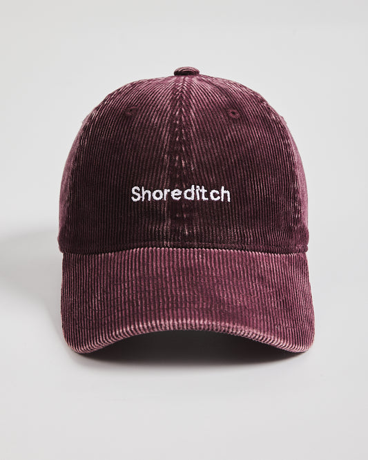 Maroon corduroy cap with 'Shoreditch' text on a light gray background