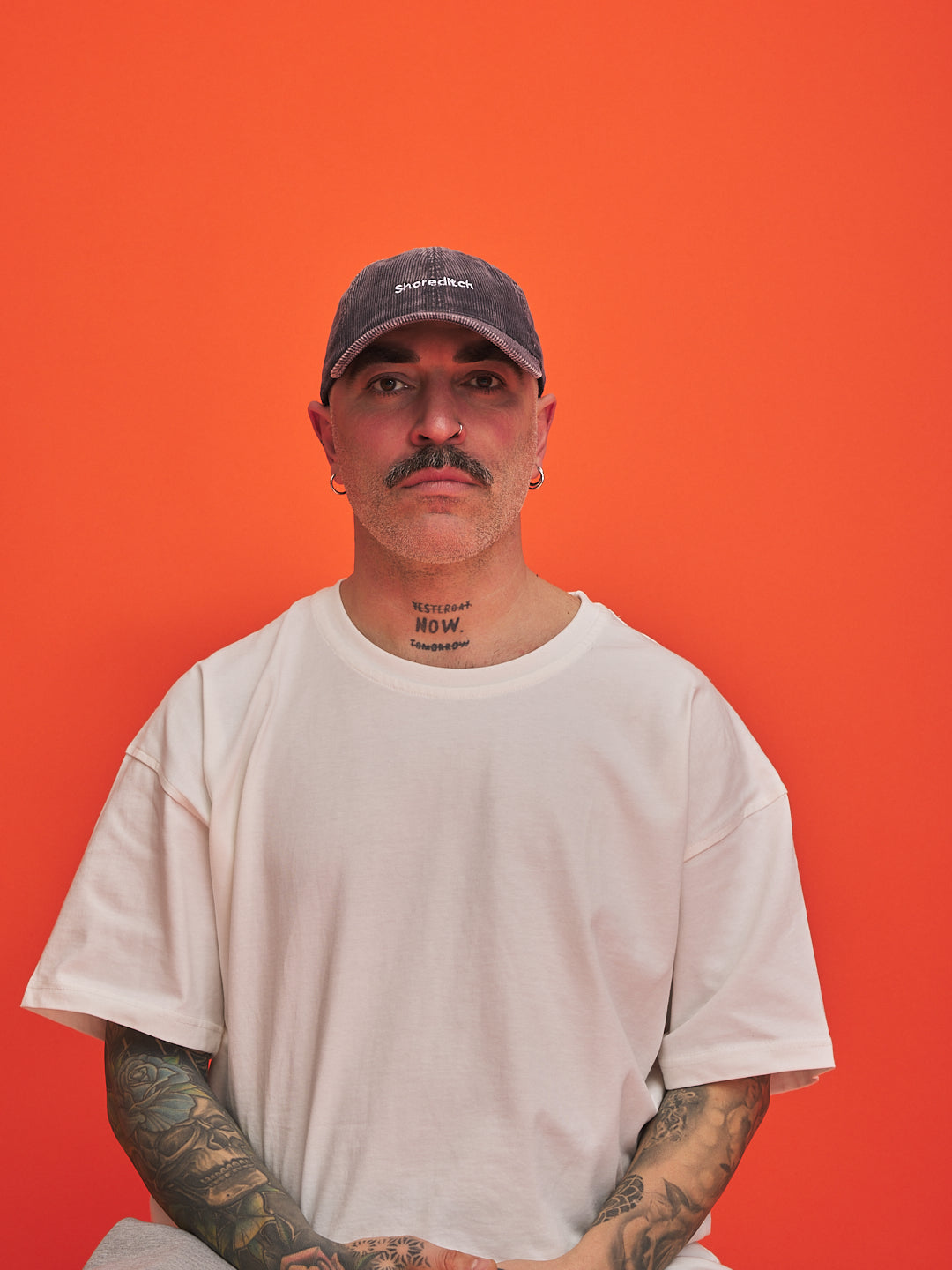 Person wearing a grey cap and white t-shirt against an orange background