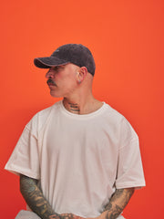 Person wearing a cap and white t-shirt against an orange background
