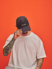 Person wearing a grey cap with 'Shoreditch' branding against an orange background