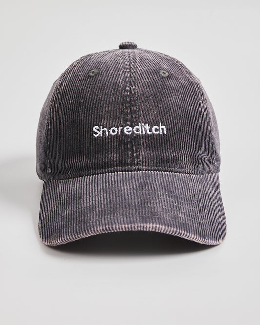 Gray corduroy cap with 'Shoreditch' text on a light gray background