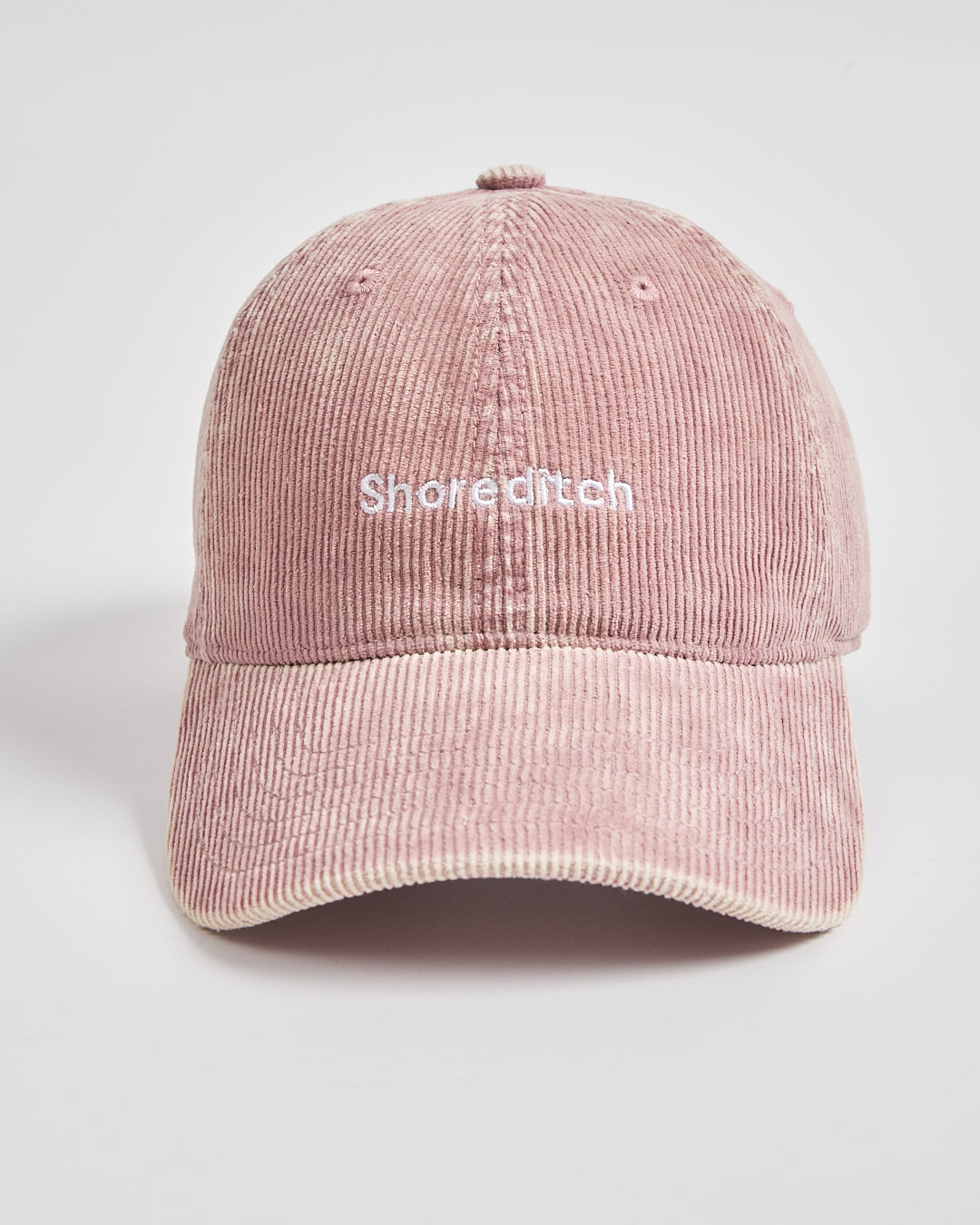 Pink corduroy cap with 'Shoreditch' text on a light gray background