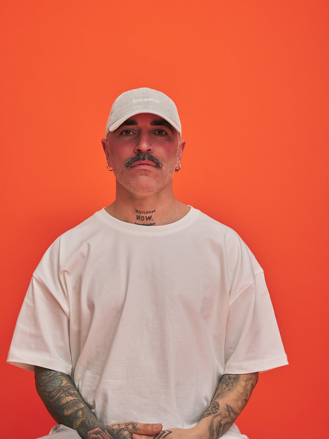 Man wearing a white cap and t-shirt against an orange background