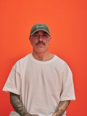 Man wearing a green cap and white t-shirt against an orange background