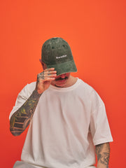 Person wearing a green cap with 'Shoreditch' text on an orange background