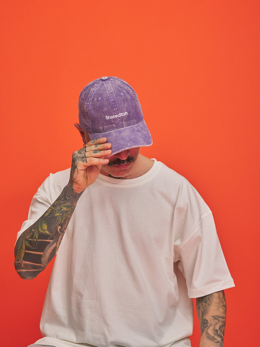 Person wearing a purple cap with text on an orange background