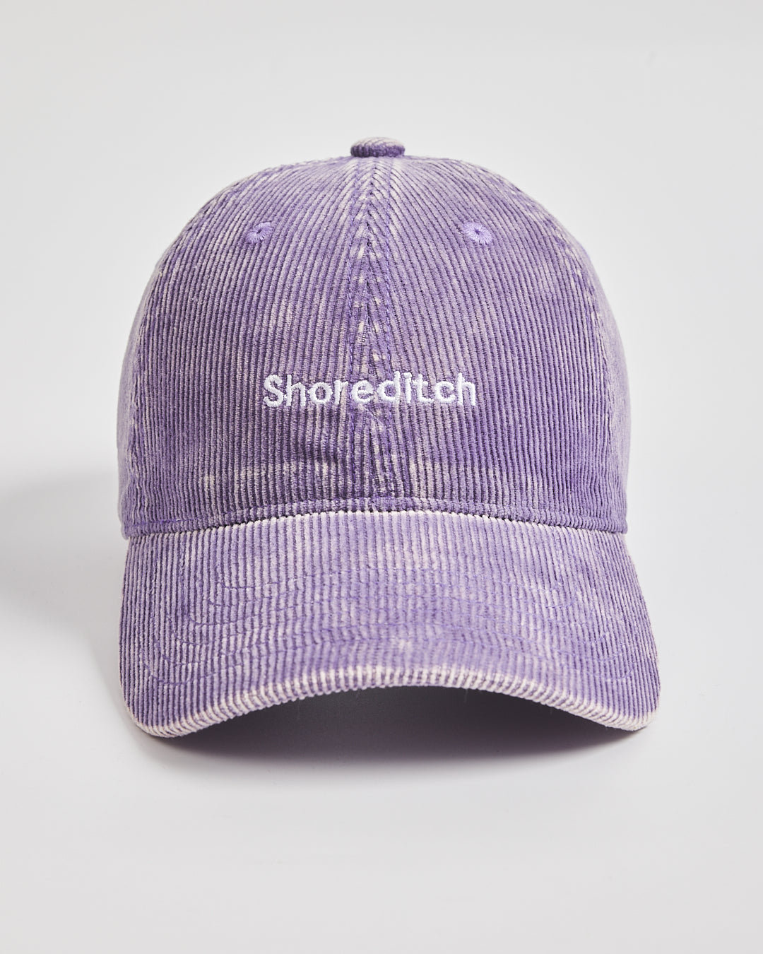 Purple corduroy cap with 'Shoreditch' text on a light gray background