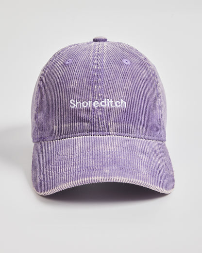 Purple corduroy cap with 'Shoreditch' text on a light gray background