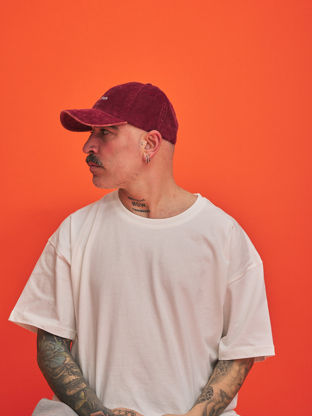 Man wearing a red cap and white t-shirt against an orange background