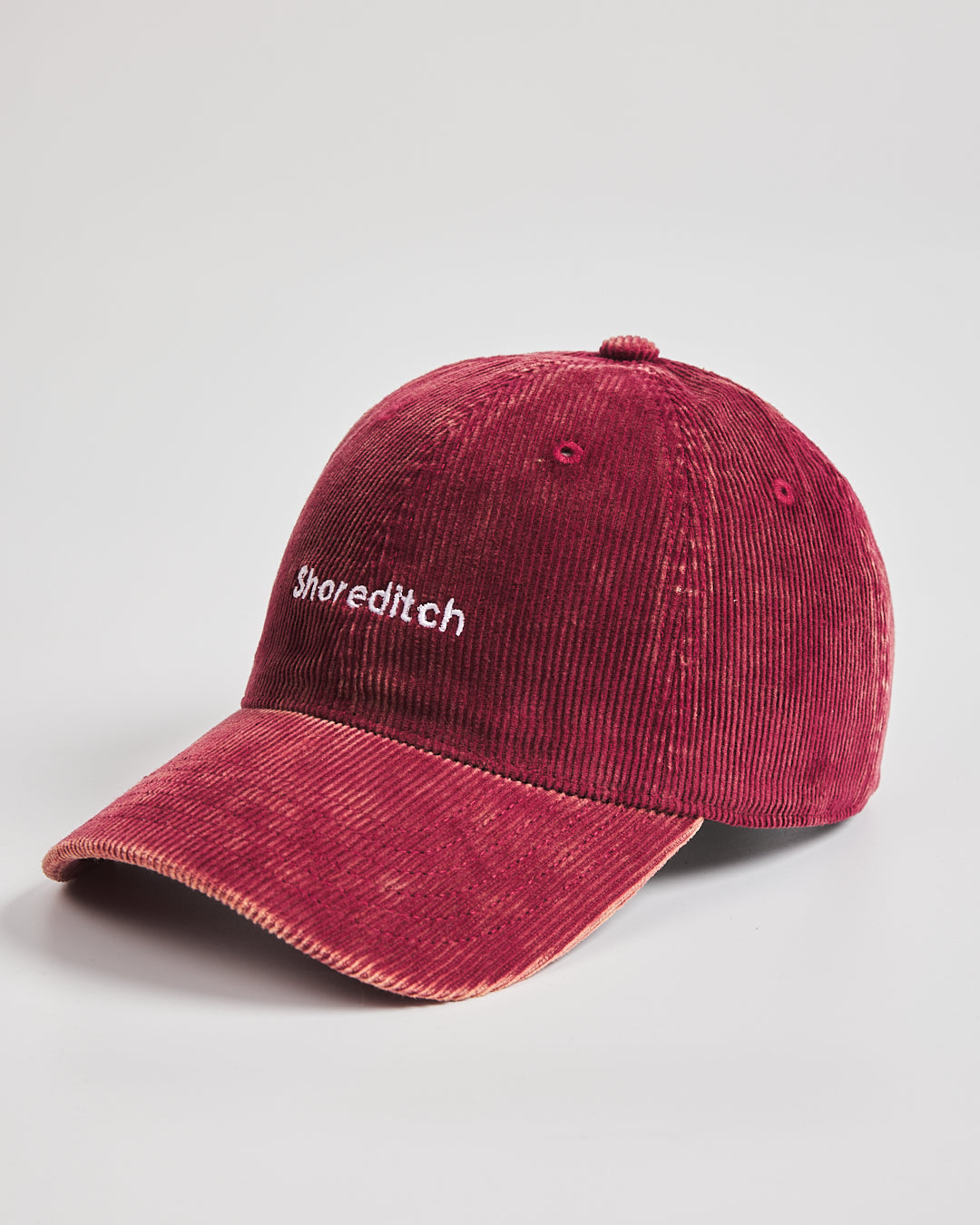 Red cap with 'Shoreditch' text on a light gray background