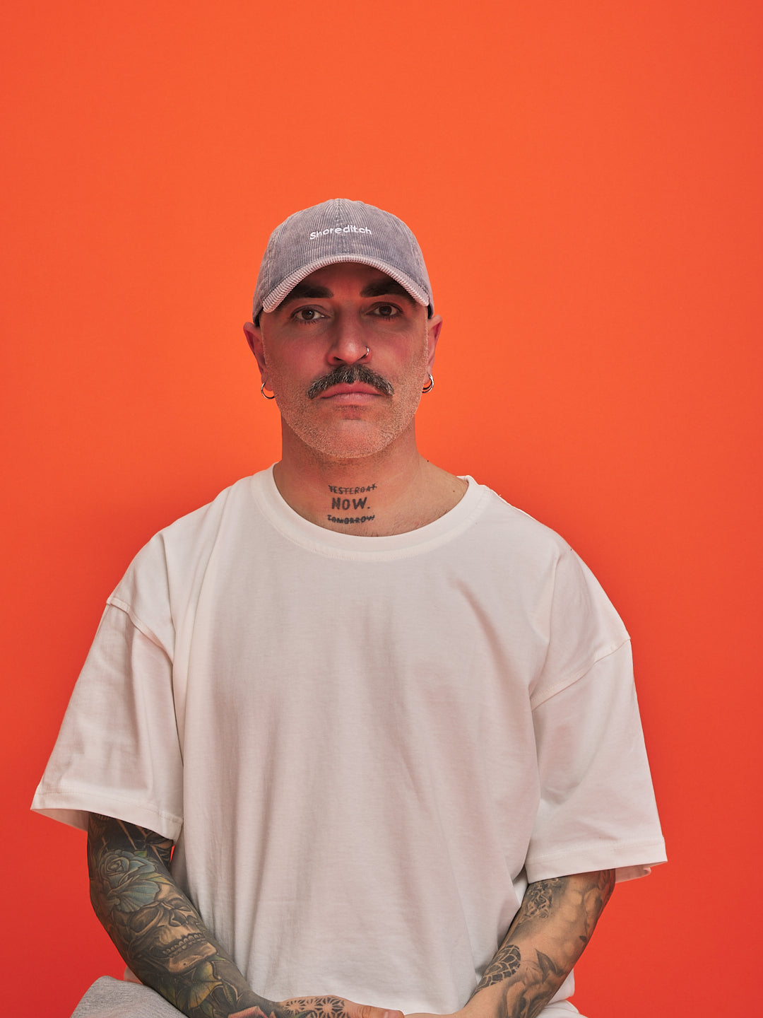 Man wearing a cap and white t-shirt against an orange background