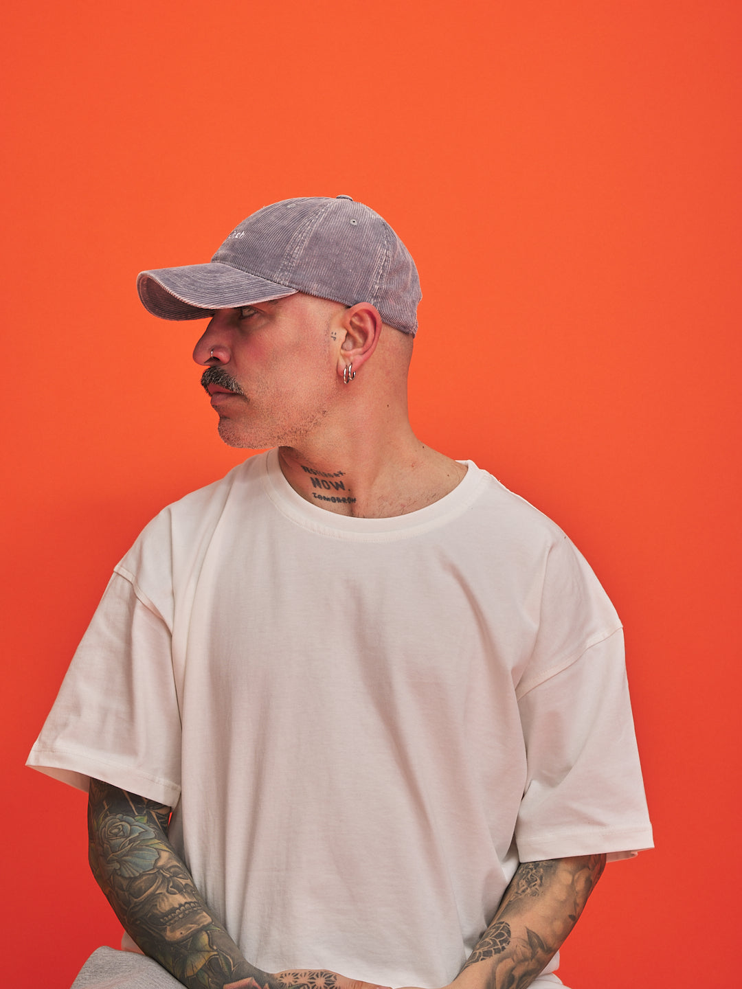 Man wearing a gray cap and white t-shirt against an orange background