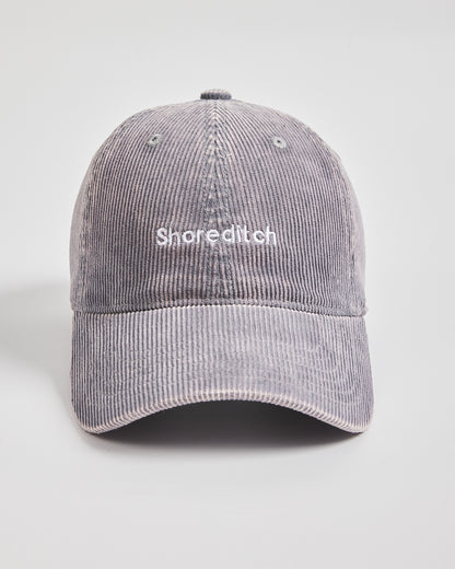 Gray corduroy cap with 'Shoreditch' text on a light gray background