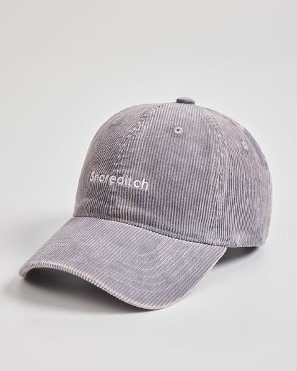 Gray corduroy cap with 'Shoreditch' branding on a light gray background