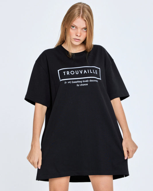 Person wearing a black oversized t-shirt with 'TROUVAILLE' text on a plain background
