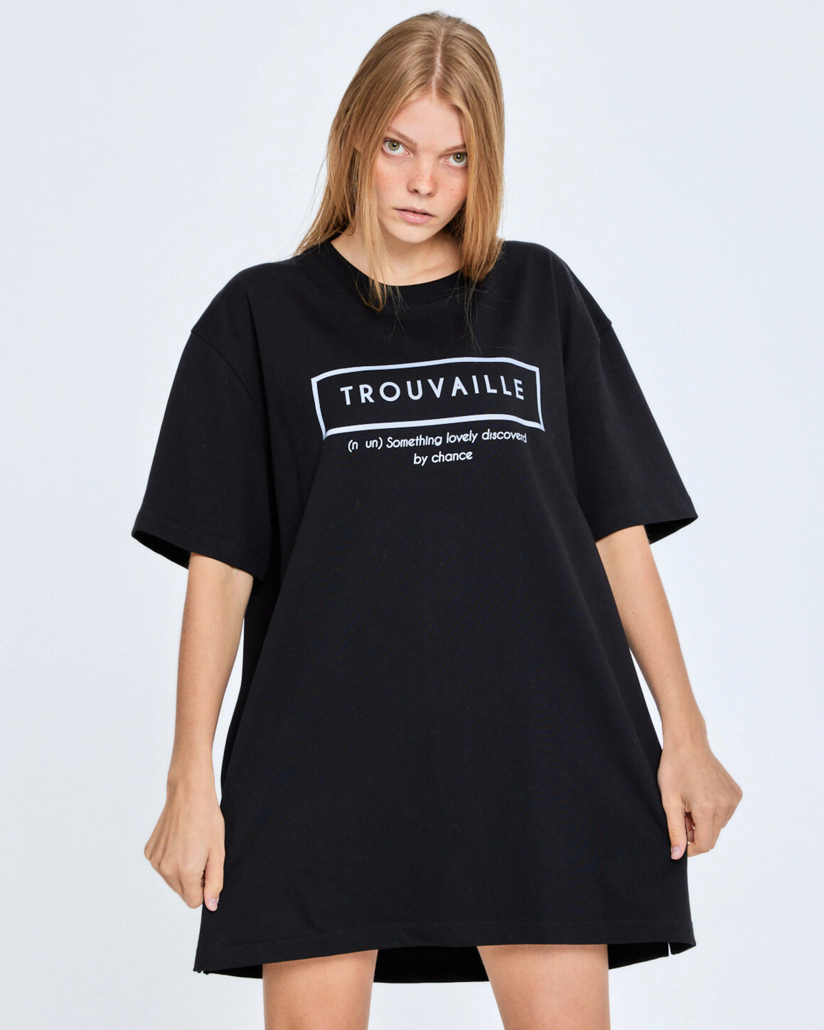 Person wearing a black oversized t-shirt with 'TROUVAILLE' text on a plain background