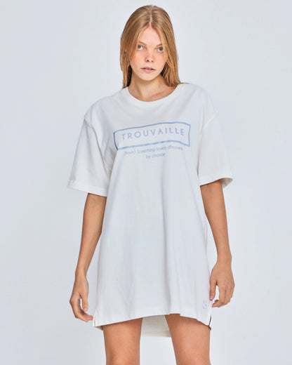 Person wearing a white oversized t-shirt with 'Trouvaille' logo on a light gray background