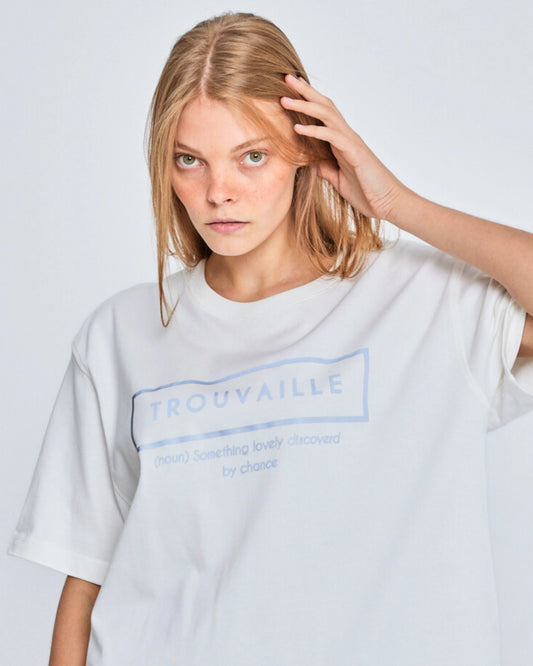 Person wearing a white t-shirt with 'Trouvaille' branding on a plain background