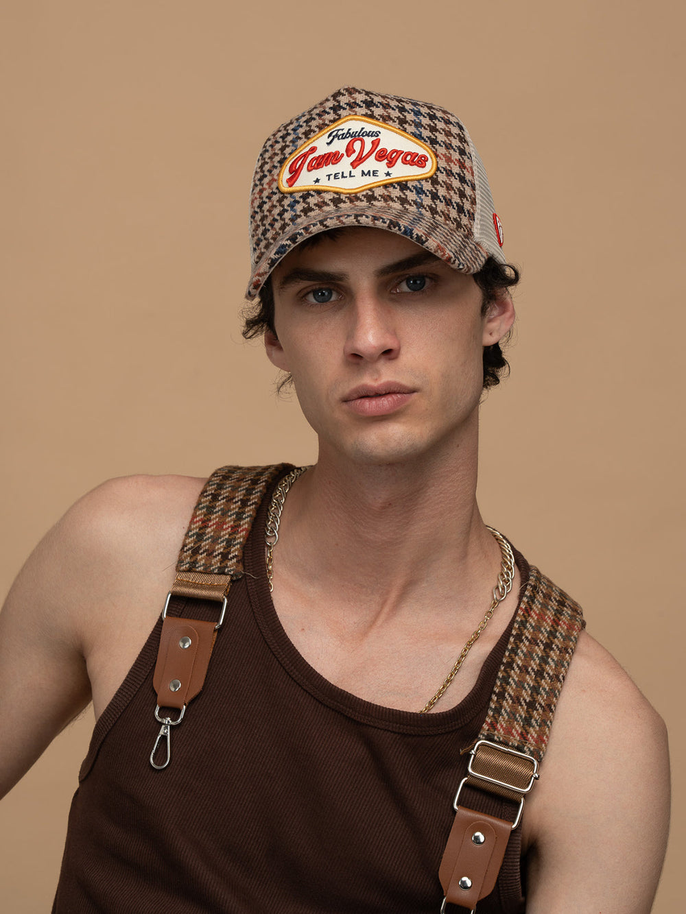 Man wearing Vegas Beige Trucker Hat and suspenders against a beige background