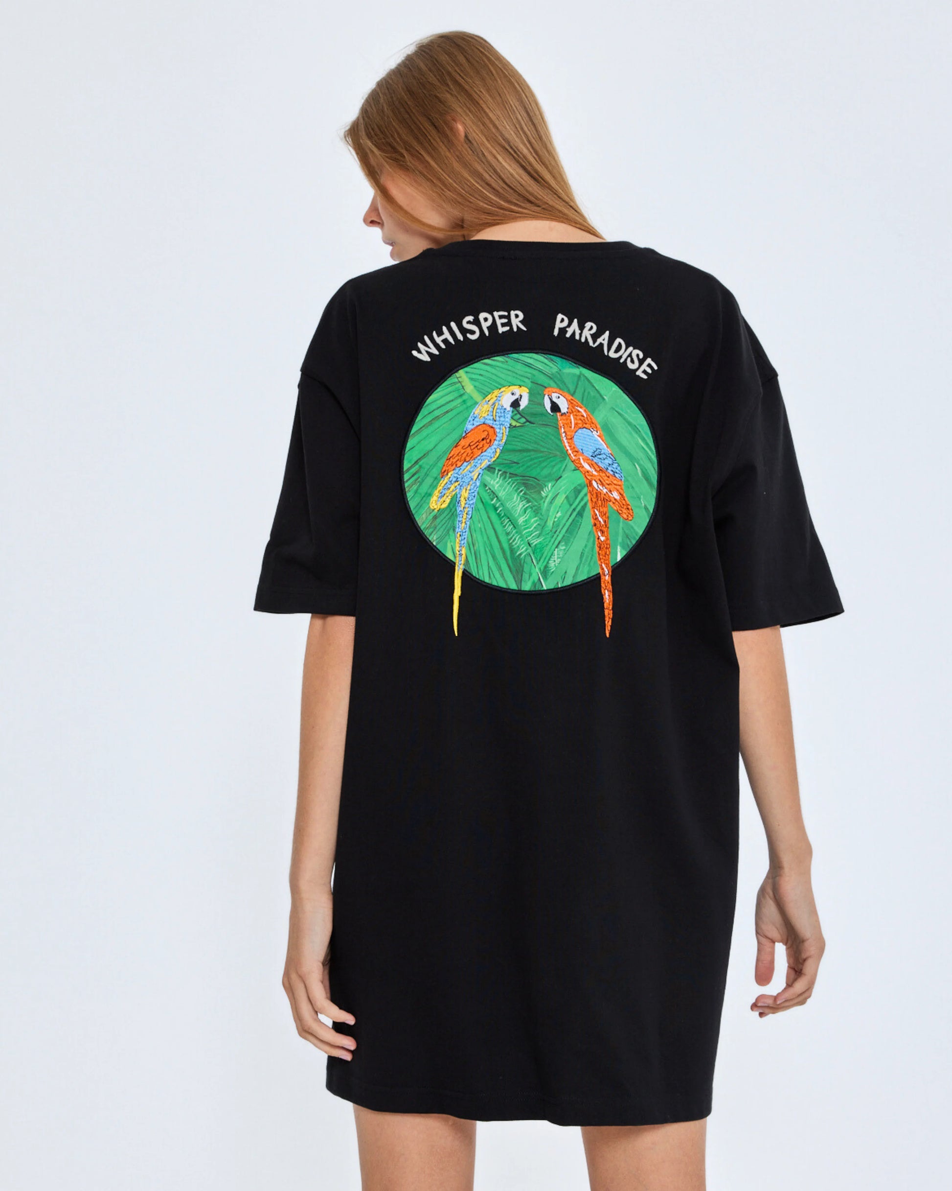 Black t-shirt with parrot design and 'Whisper Paradise' text on a white background