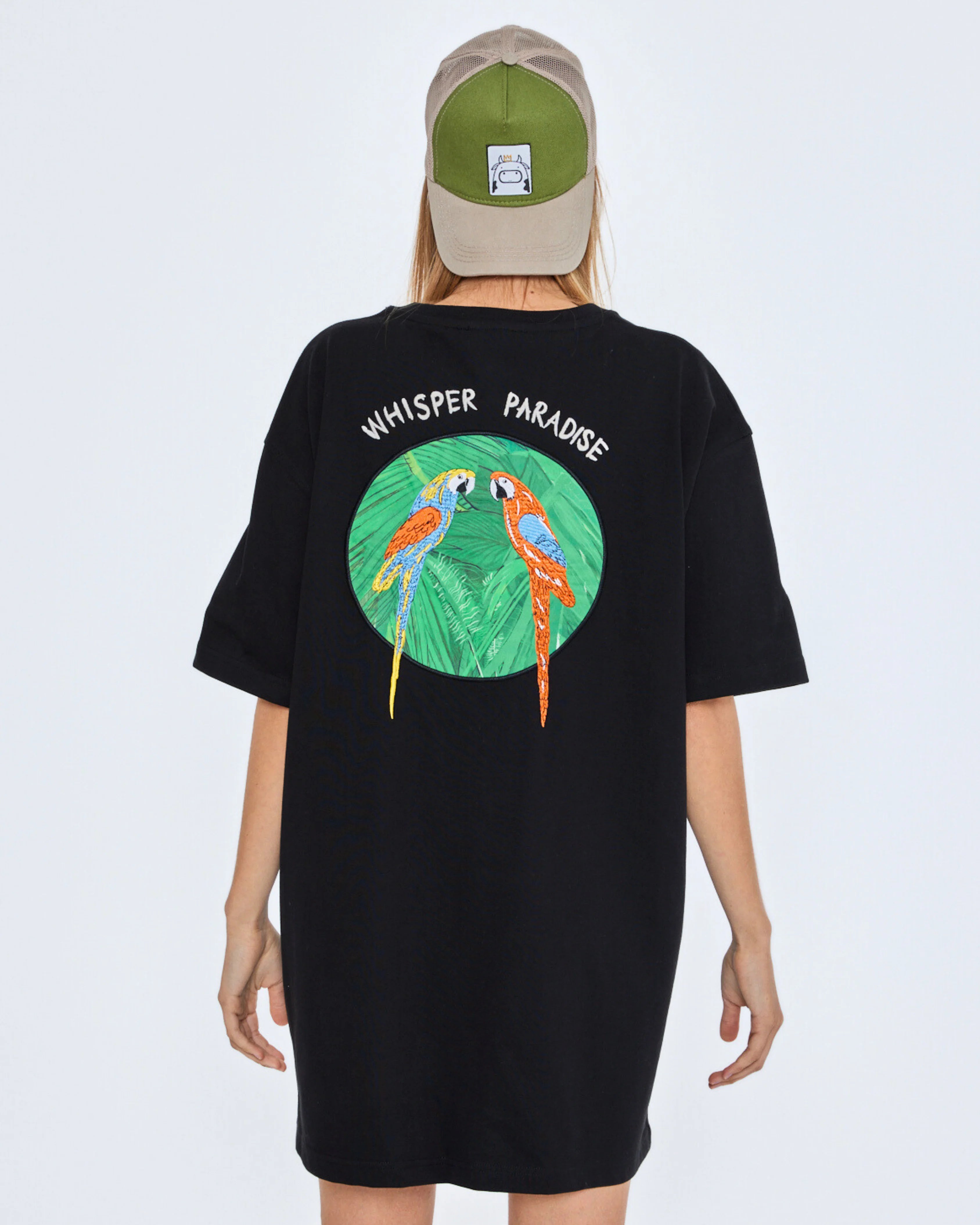 Black t-shirt with parrot design and 'Whisper Paradise' text on the back, worn by a person.