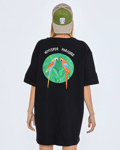 Black t-shirt with parrot design and 'Whisper Paradise' text on the back, worn by a person.