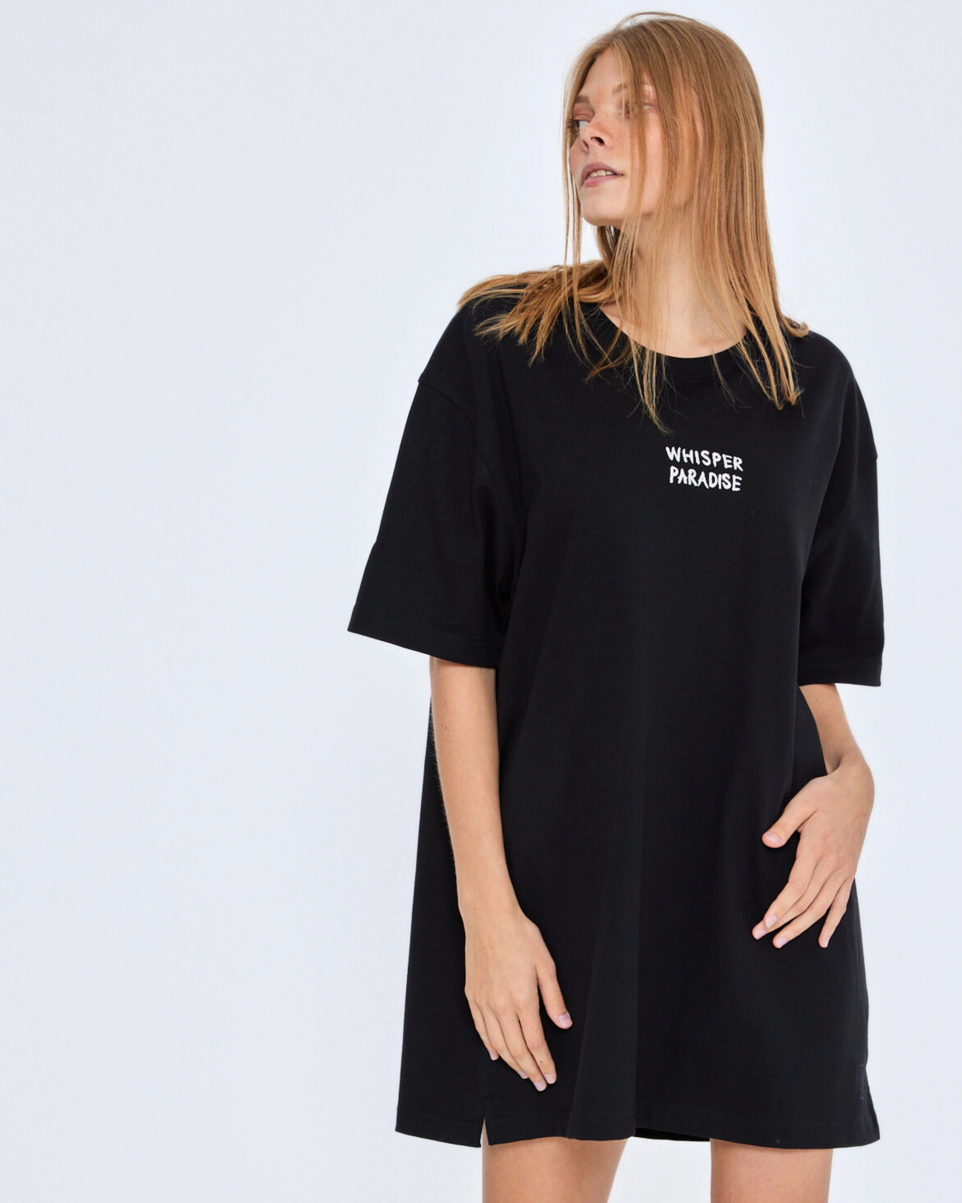 Person wearing a black t-shirt with 'Whisper Paradise' text on a white background