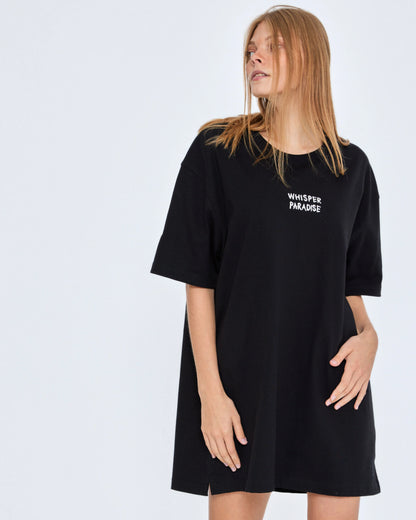Person wearing a black t-shirt with 'Whisper Paradise' text on a white background
