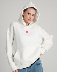 Person wearing a white hoodie with a small red logo on a gray background