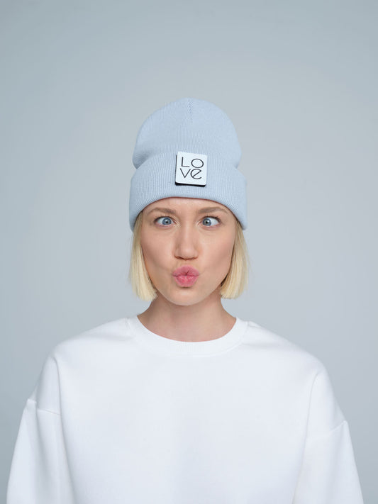 A person wearing a baby blue beanie with a 'Love' text design patch on the front.