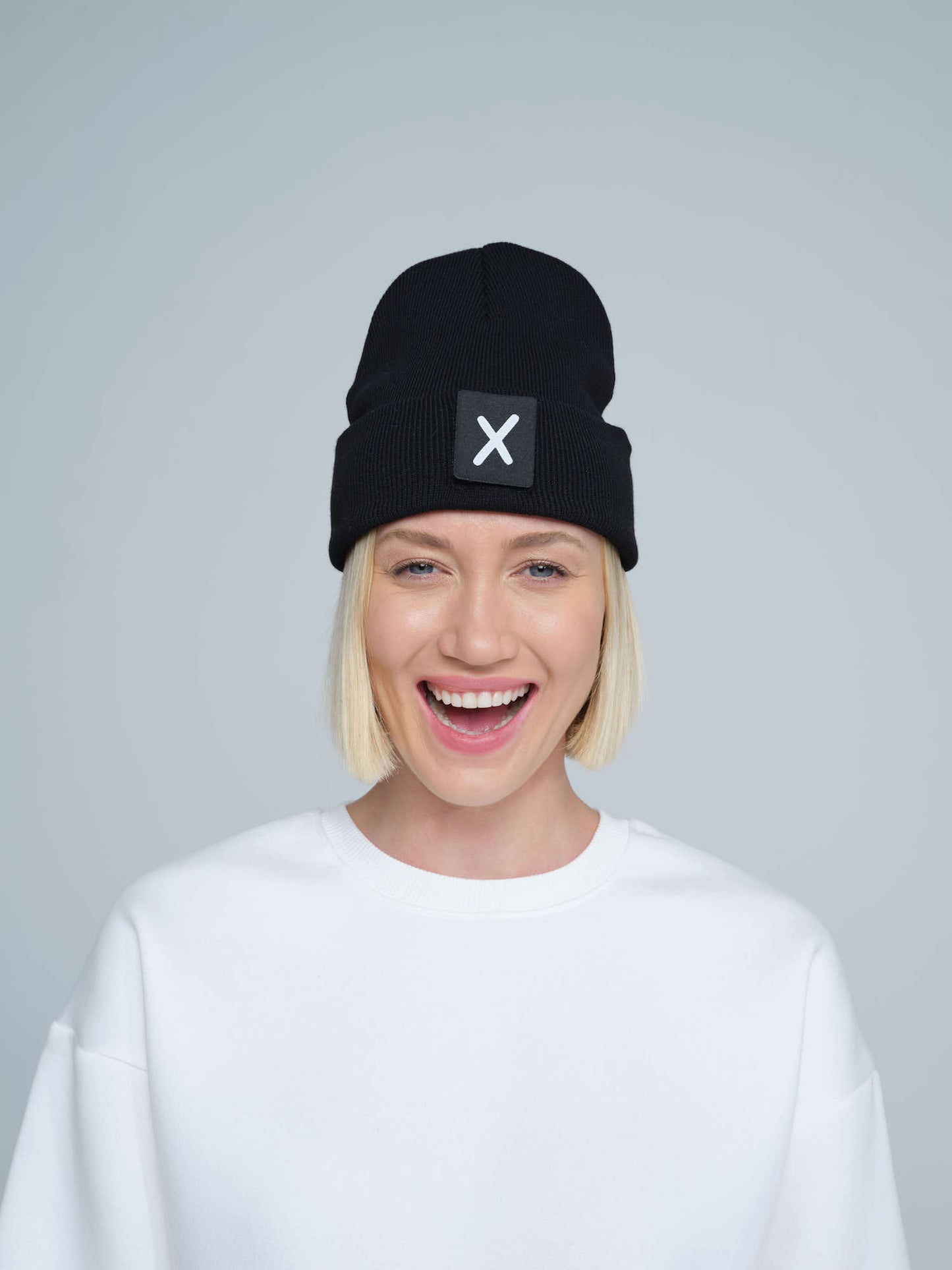 women wearing black beanie with X letter patch on it