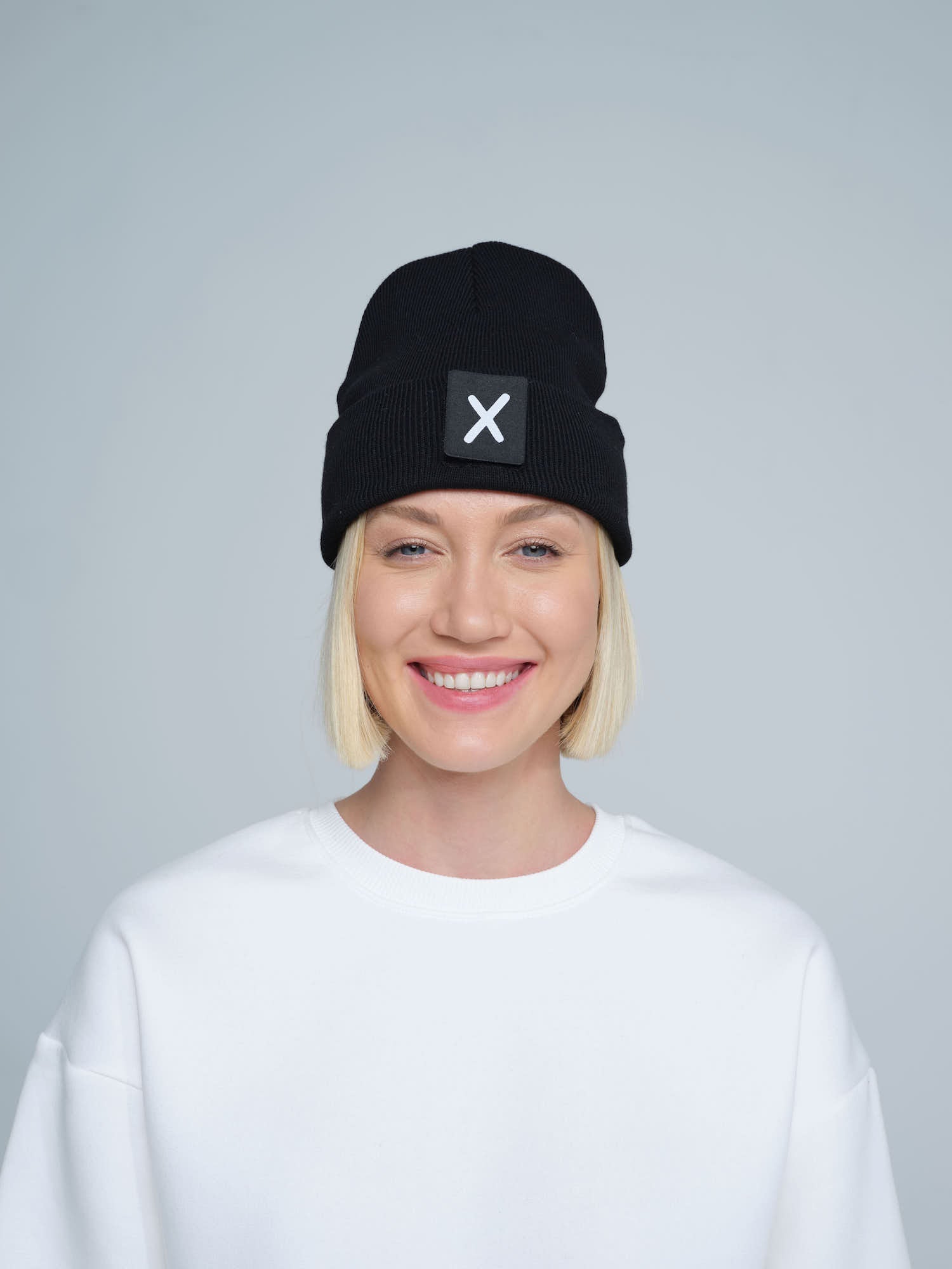women wearing black beanie with X letter patch on it with smiley face