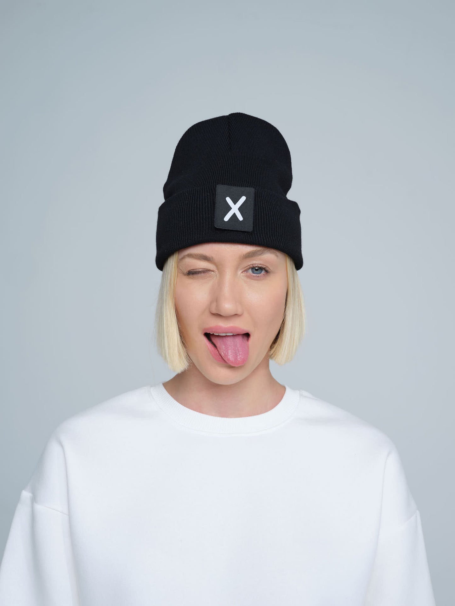 women wearing black beanie with X letter patch on it