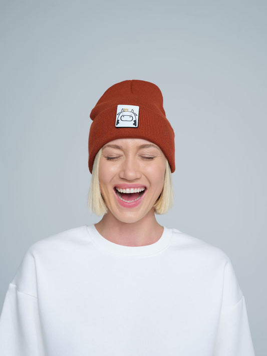woman wearing burnt orange beanie with a cow patch on the front 