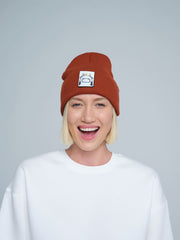 woman wearing burnt orange beanie with a cow design patch on the front 