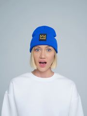A female person wearing a cobalt blue beanie with a crown design patch on the front.