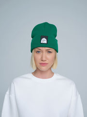 female model wearing dark green beanie with a 'duck' patch on the front