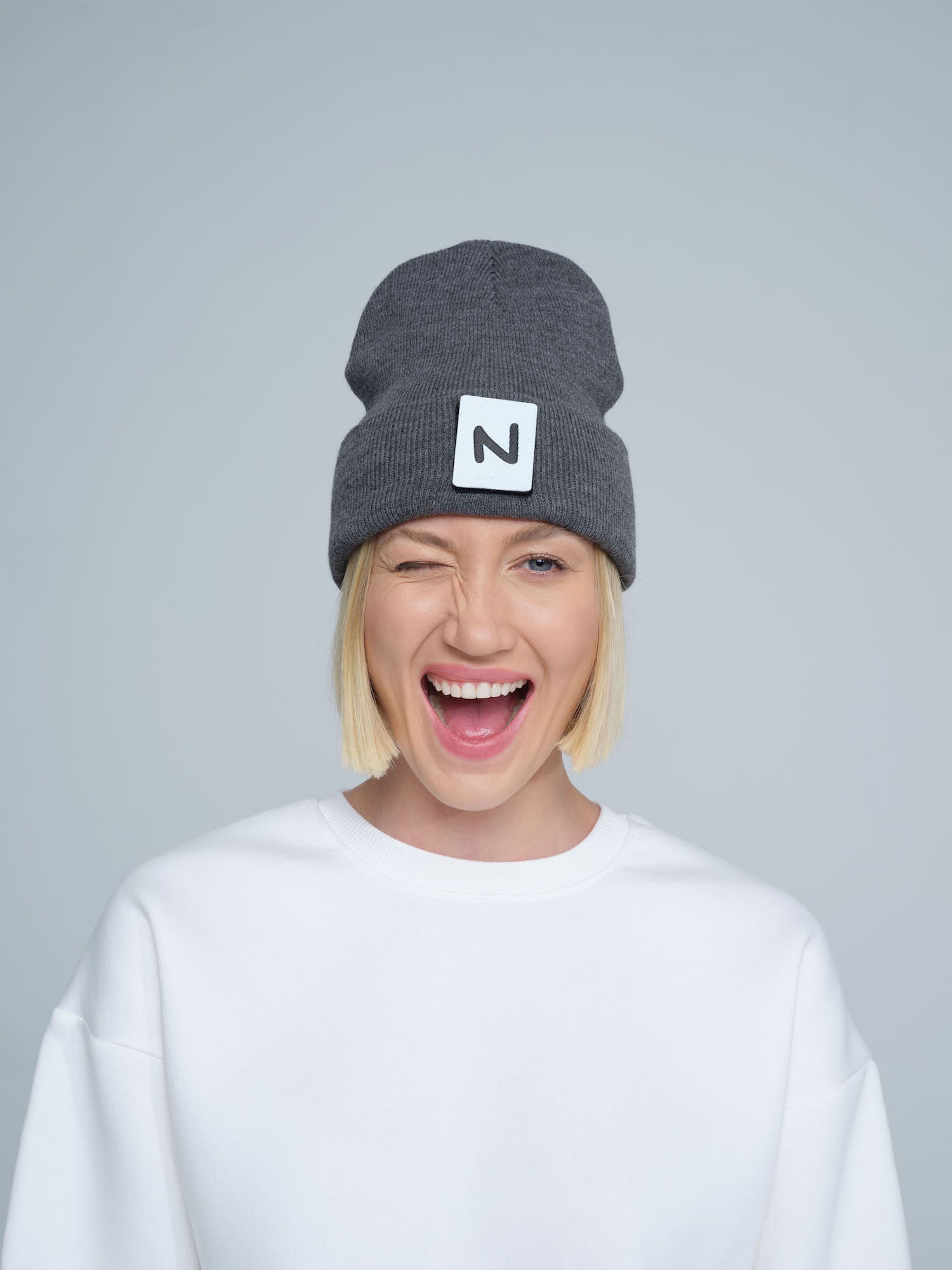 women model wearing dark grey patch ready beanie with 'N' letter patch on the front