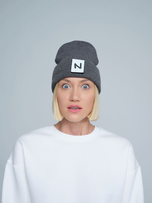women model wearing dark grey patch ready beanie with 'N' letter patch on the front