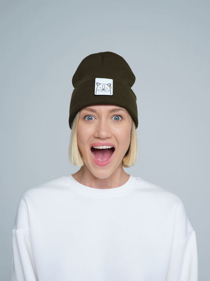 A person wearing a dark olive green beanie with a design on the cuff, paired with a white t-shirt.